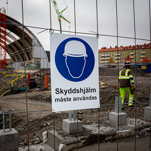 Påbudsskylt på staket, använd skyddshjälm